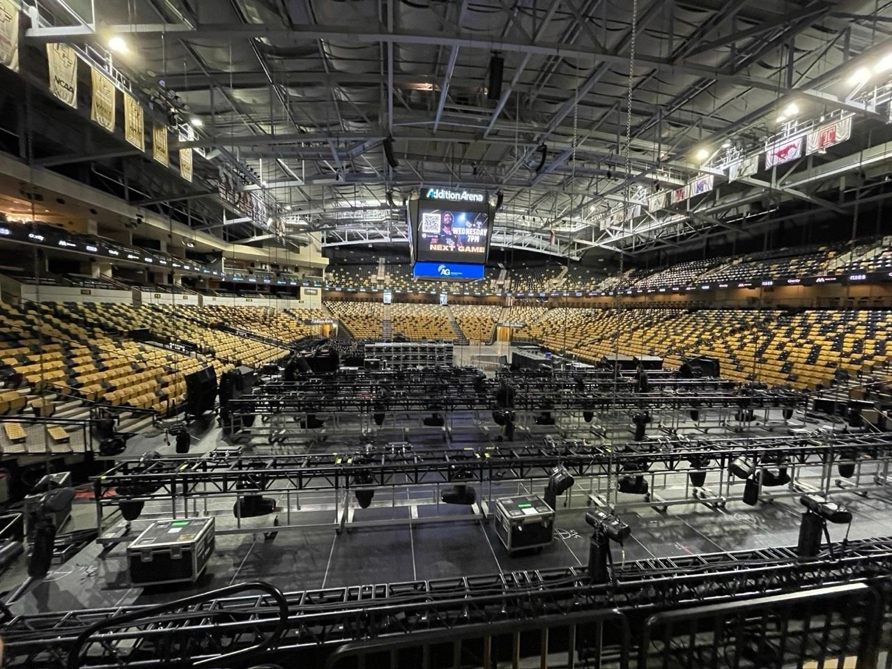 Stage and gear being set up on the floor of an empty arena